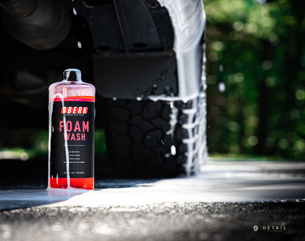 OBERK Foam Wash bottle next to a car tire with soap suds, outdoors.