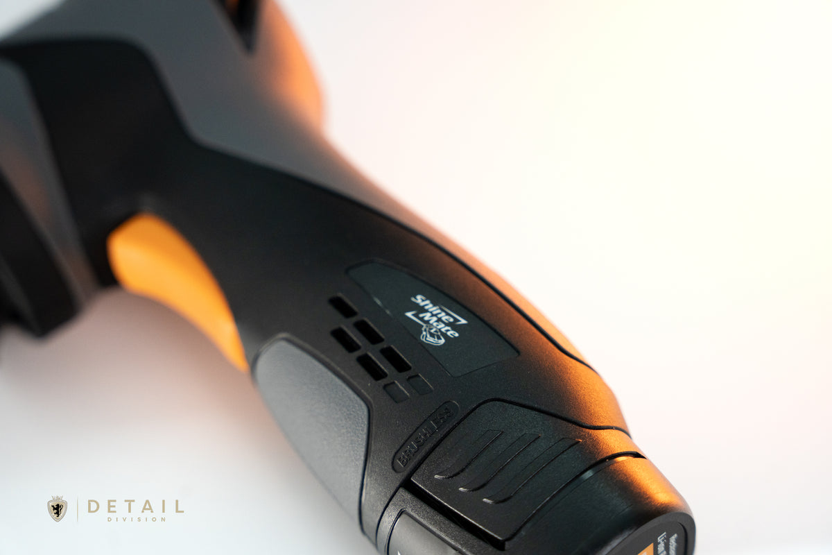 Close-up of a black and orange power tool with &#39;Detail&#39; branding on a white background